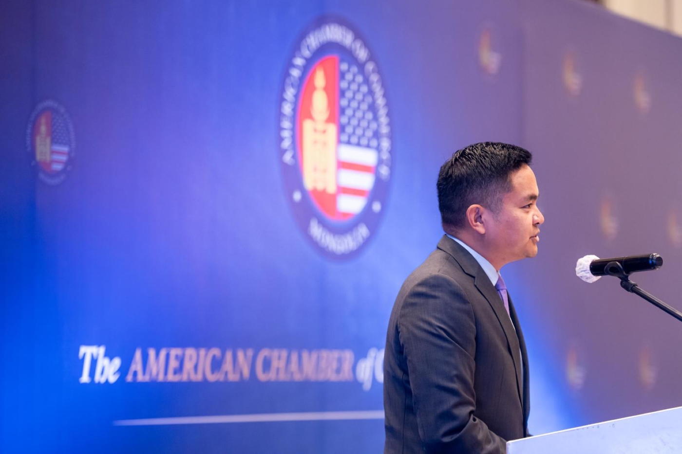 A speaker at the AmCham Mongolia lectern in front of the chamber seal